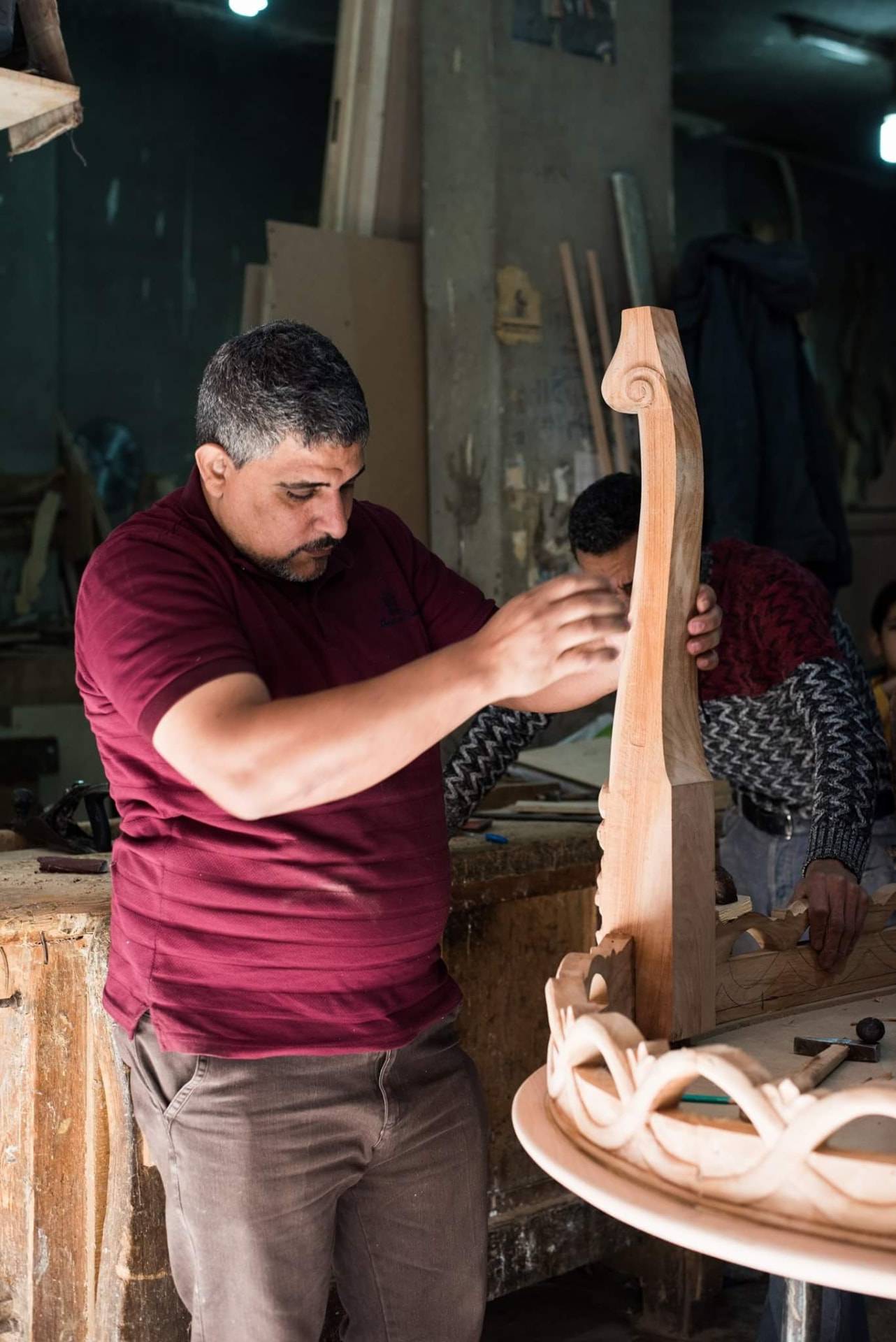 Craftsman shaping a carved beech table leg on the factory floor